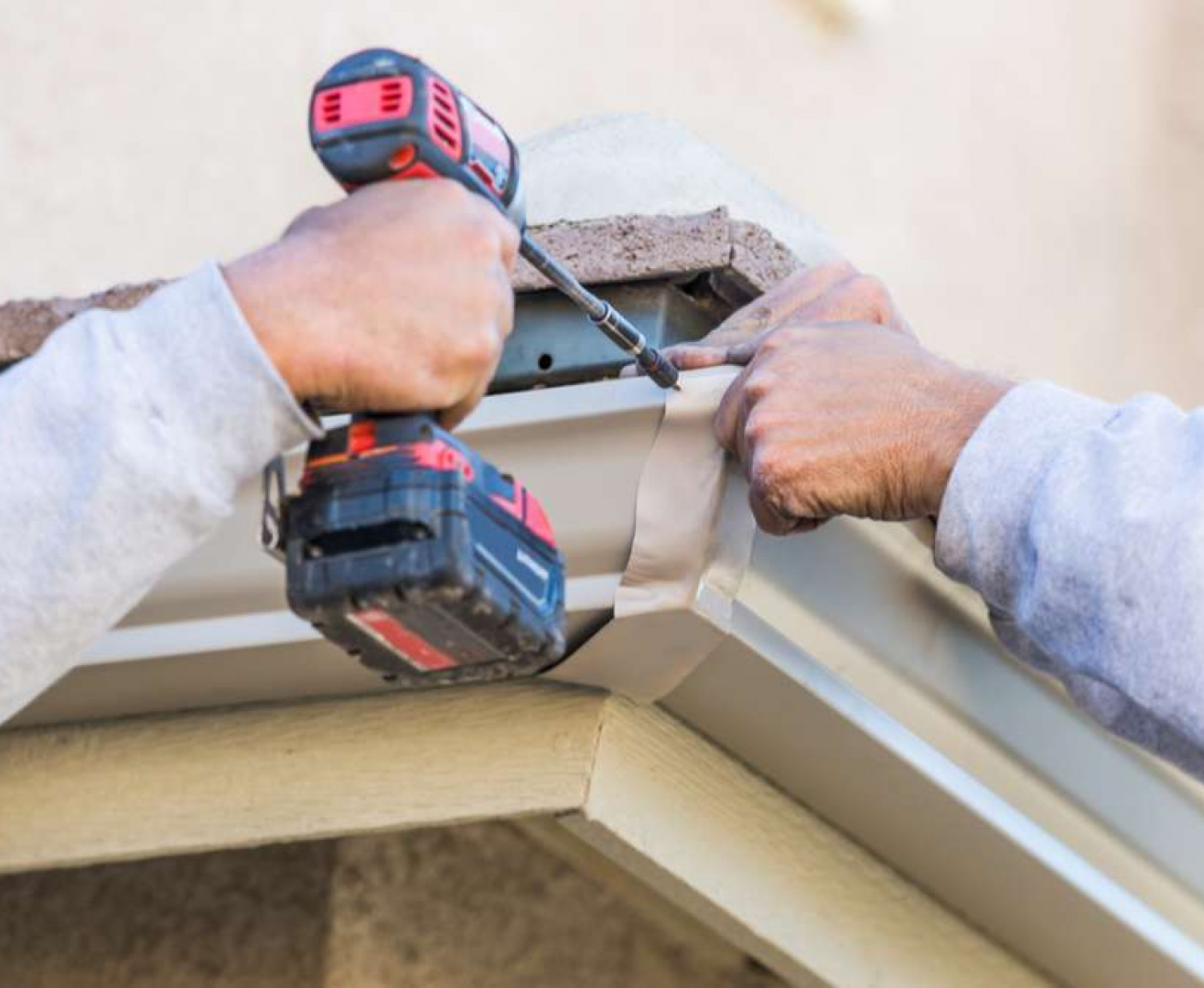 gutters 2 A sunlit brick wall of a commercial building with a smooth concrete pathway and blue sky above. Security cameras are mounted on the wall.